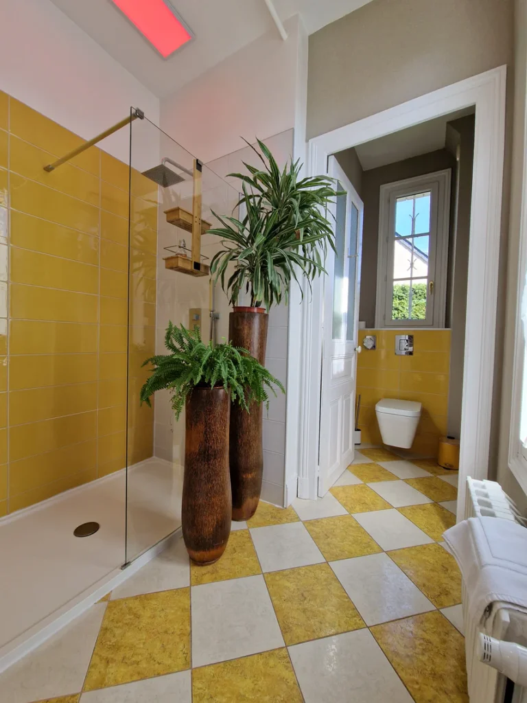 La salle d'eau lumineuse dispose d'une grande douche à l'italienne et de toilettes suspendues séparées.